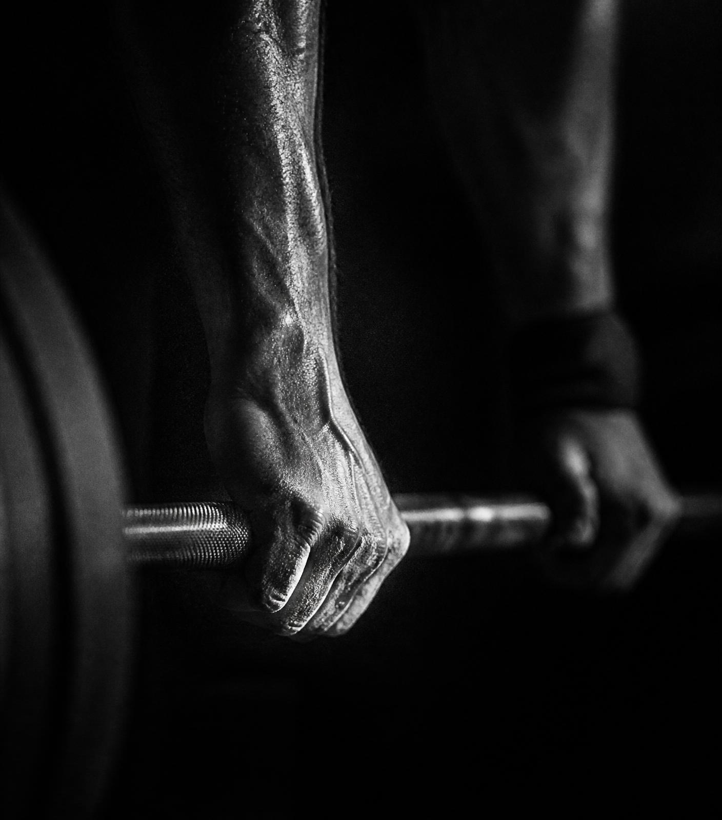 Chalked hand gripping a barbell
